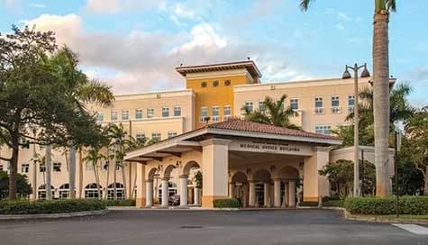 Hospital entrance canopy with palm trees and landscaped grounds