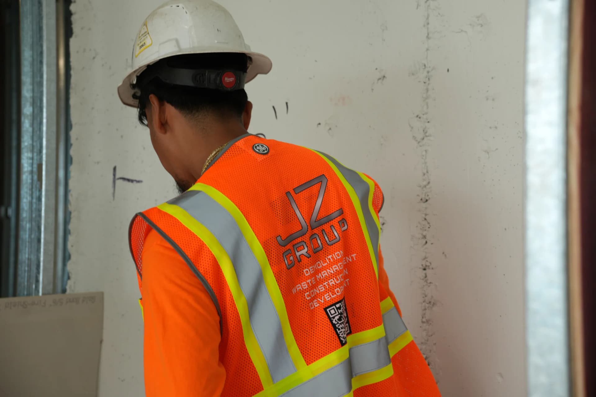 JZ Group branded safety vest beside interior framing at 100 Biscayne