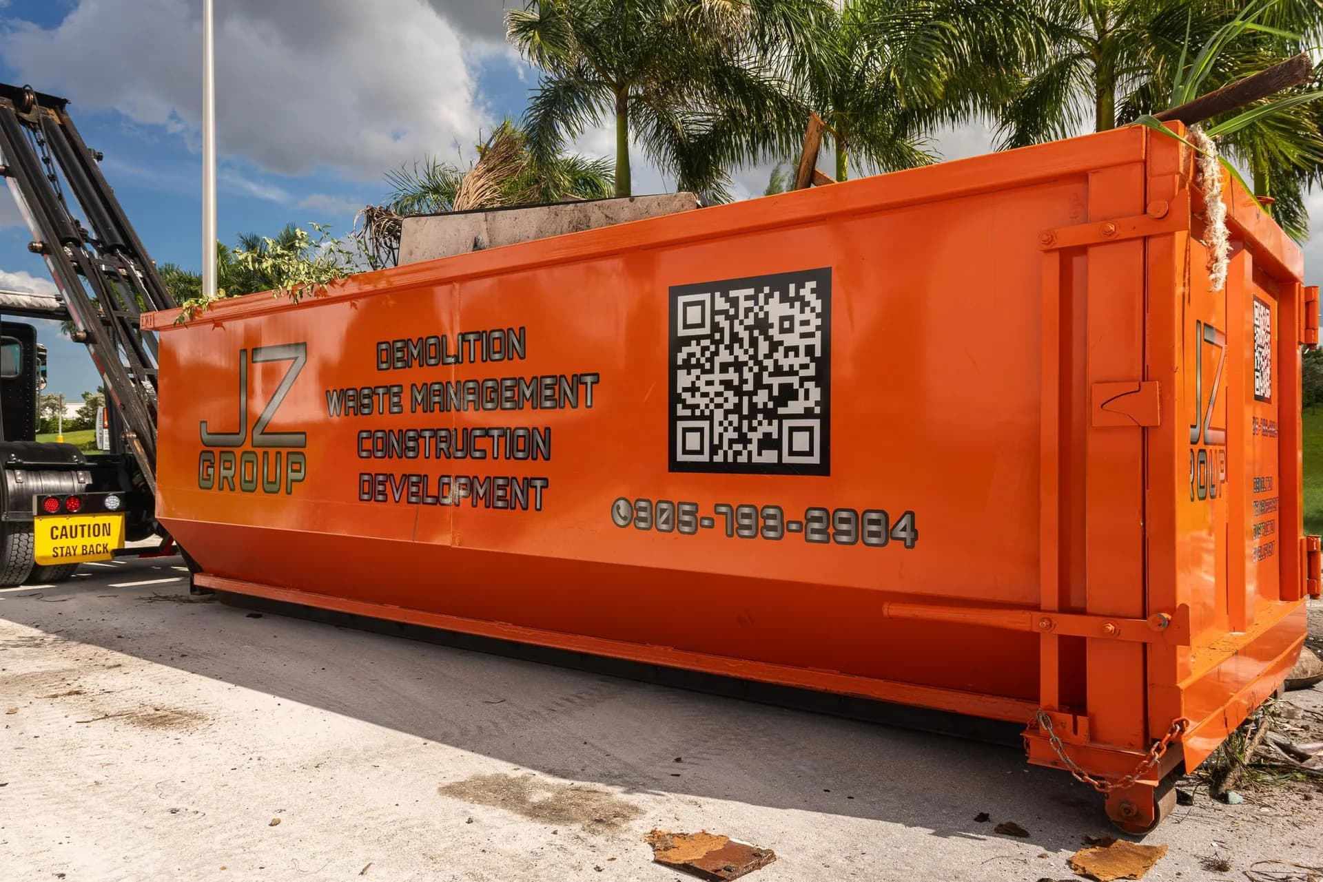 Orange JZ container beside a roll-off truck lifting mechanism