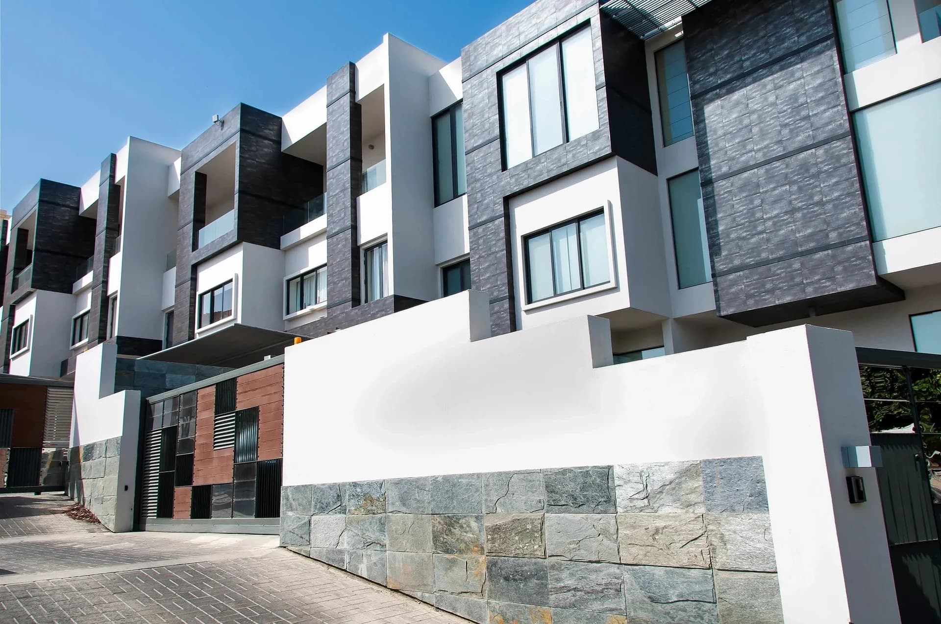 Contemporary residences with white walls, charcoal stone panels and recessed balconies