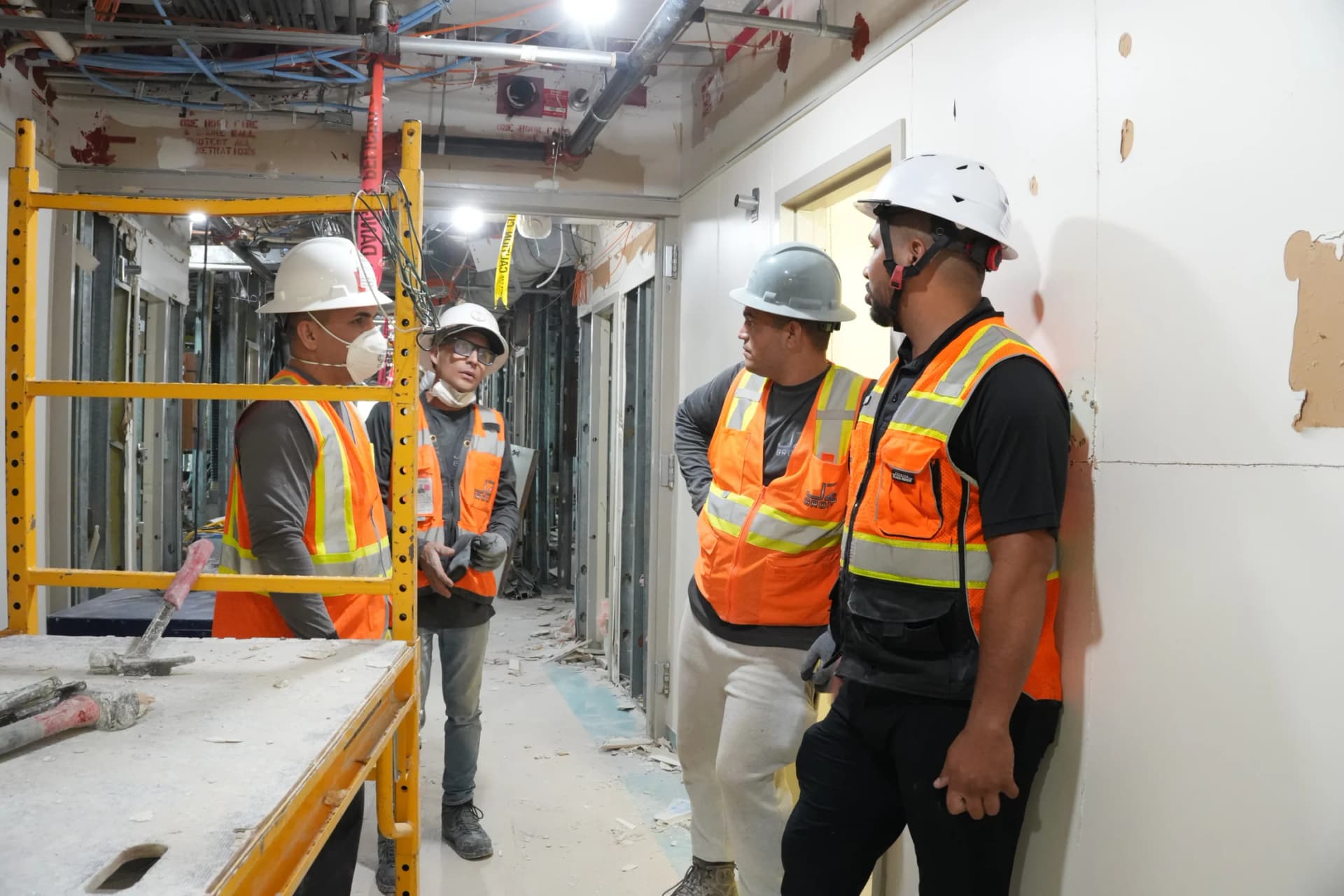 Four JZ crew members in protective equipment discussing work at the UHealth Tower penthouse